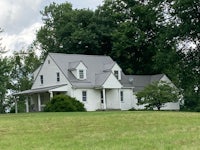 a white house sits on top of a grassy field