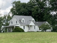 a white house sits on top of a grassy field